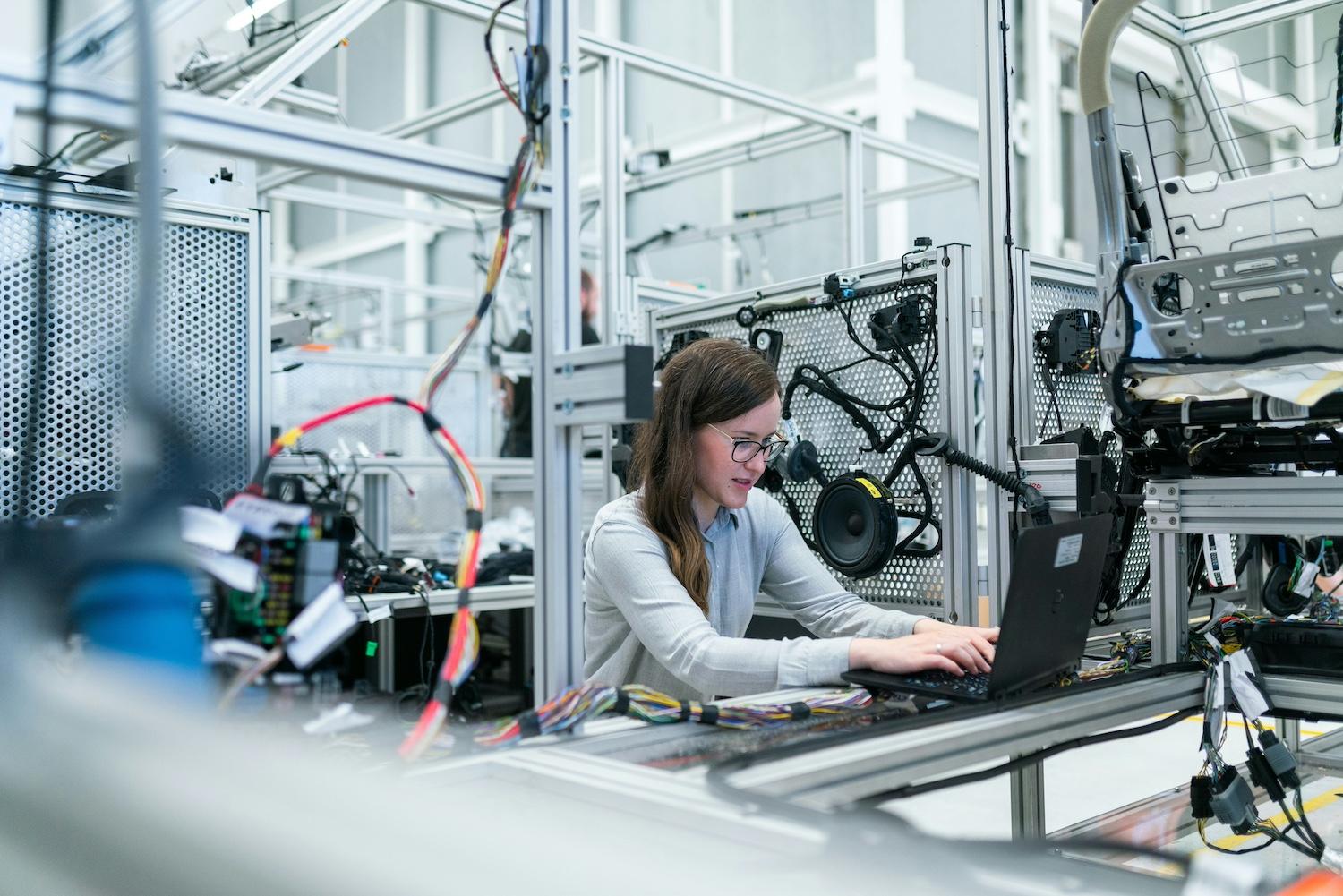 A woman works on a laptop in a factory — DEI